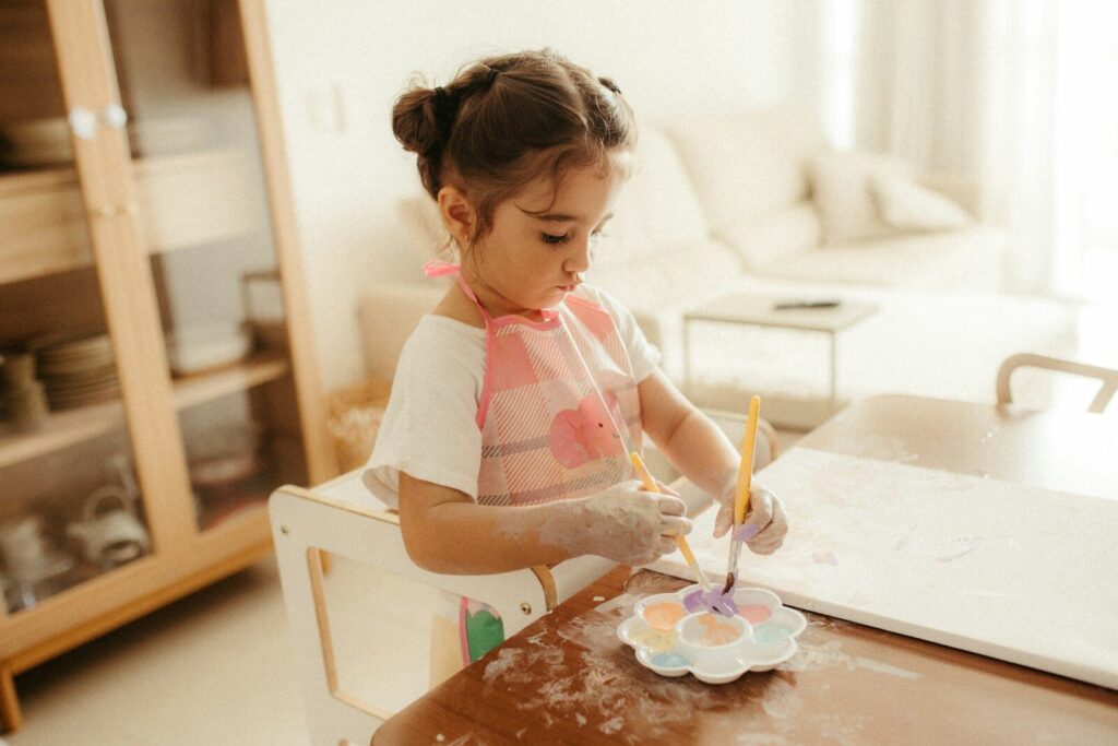A young girl paints at a table with watercolors.